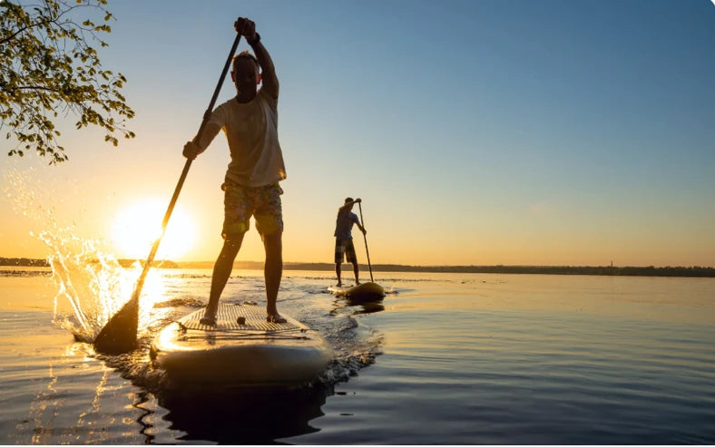Zwei Menschen beim Stand-up-Paddling im Sonnenuntergang